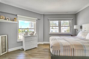 A bedroom with a large bed, two windows, a dresser, and a wall-mounted shelf with decorative items. - Intracoastal Bliss at FL Yacht & Beach Club (Fort Lauderdale)