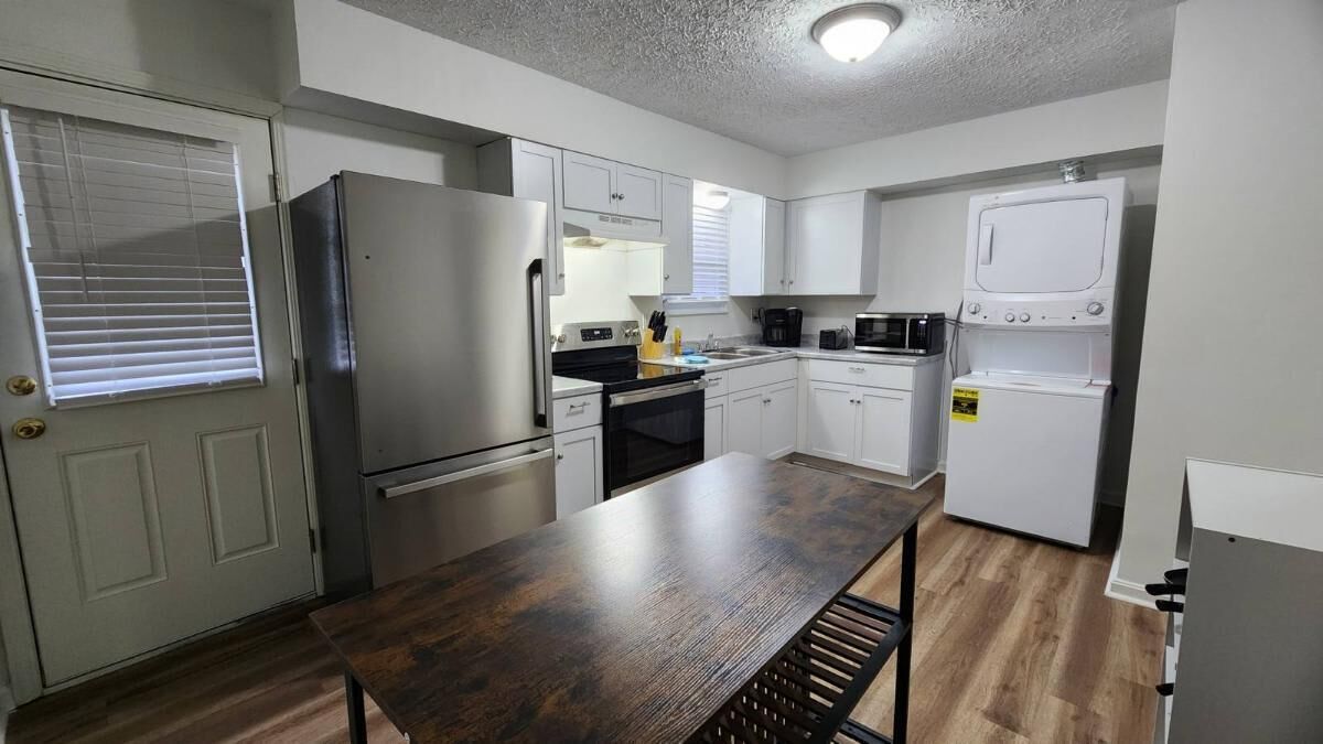 A compact kitchen with a refrigerator, stove, microwave, and a washing machine.