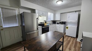 A compact kitchen with a refrigerator, stove, microwave, and a washing machine. - King Bed| Pet Friendly |2BR Townhome with Parking (Louisville)