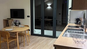 Une cuisine moderne avec une table à manger en bois, un évier encastré et un téléviseur fixé au mur.