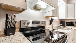 A kitchen with a stainless steel stove, a microwave, and a knife block.