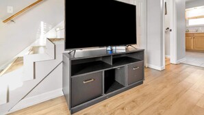 A modern living room with a flat-screen TV mounted on a dark wooden entertainment unit. - Spacious Town Home | Free Parking | Pet Friendly (Louisville)