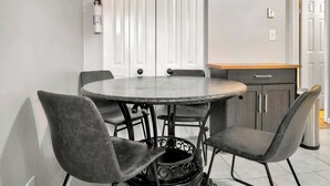 A round dining table with four chairs, a fire extinguisher on the wall, and a cabinet with a wooden countertop. - Spacious Town Home | Free Parking | Pet Friendly (Louisville)