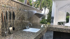 A kitchen with granite countertops, a stainless steel sink, and hanging utensils. - FERN COTTAGE:  Beautiful Studio, Only Steps Away From Grace Bay Beach and Strip! (Grace Bay)