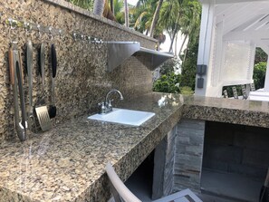 Eine Küche mit Granit Arbeitsplatten, einer Edelstahlspüle und hängenden Küchenutensilien.