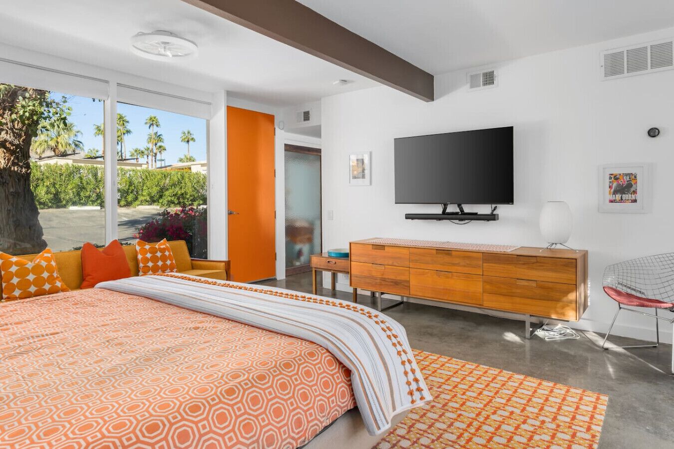 Ein modernes Schlafzimmer mit einem gro ßen Bett, einem Fernseher, einer Holzkommode und einem Sessel.