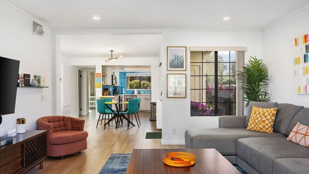 A modern living room with a sofa, a coffee table, and a dining area with chairs.