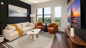 A modern living room with a sofa, two armchairs, a coffee table, and a painting of a sailboat. - 2BR Oasis w/ Gym, Parking Near Rvrwalk &Dome (San Antonio)