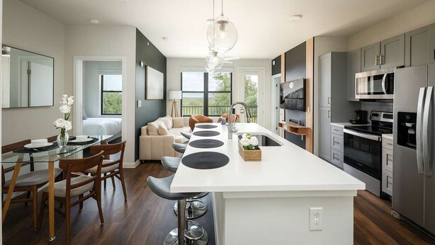A modern kitchen with a central island, stainless steel appliances, and a dining area with a glass table and chairs. - 2BR Oasis w/ Gym, Parking Near Rvrwalk &Dome (San Antonio)