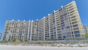 Een groot, meerlaags hotel met een gebogen gevel, nabij een zandstrand.