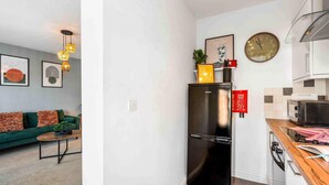 A compact kitchen with a black refrigerator, a microwave, and a wooden countertop. - Queens Cove With Seaviews By My Getaways (Worthing)