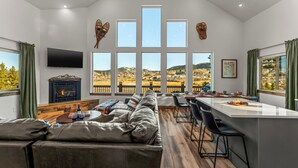 Una sala de estar moderna con un ventanal grande, una chimenea, un sofá y una zona de comedor.