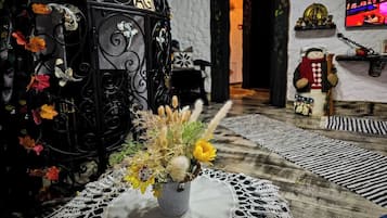 A cozy room with a decorative black gate labeled "AGI," a small table with a crocheted doily, and a television displaying a colorful scene.