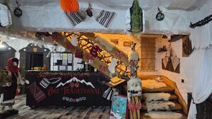 A traditional-themed room with a wooden staircase, a reception desk, and various decorations including a reindeer and a sign that reads "no ho ho ho".