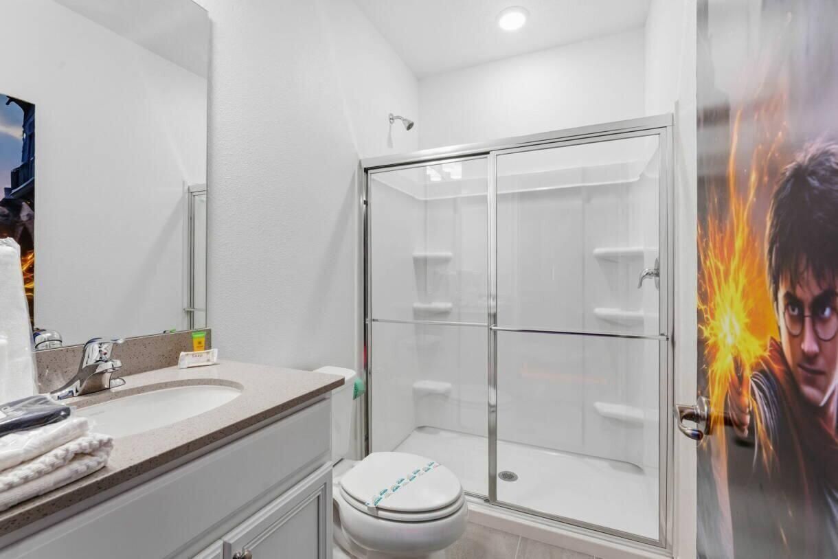 Een moderne badkamer met een douchecabine van glas, een wastafel met spiegel en een toilet.