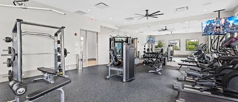 A gym with various exercise equipment, including a squat rack, bench press, and treadmills.