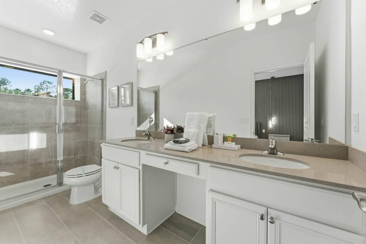 A modern bathroom with a glass shower enclosure, a double sink vanity, and a large mirror.