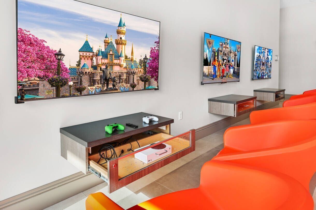 Una stanza con un grande quadro a tema Disney, una console di gioco e una TV.