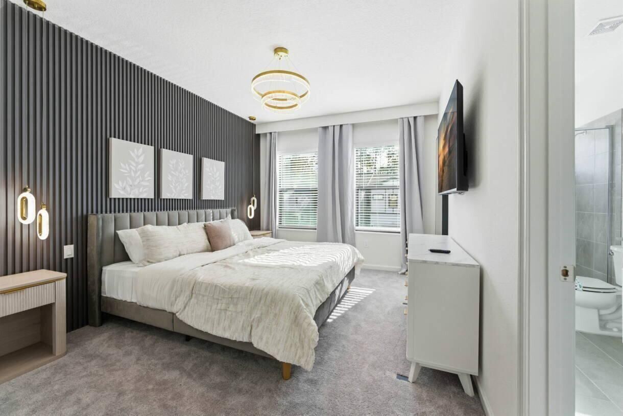 Ein modernes Schlafzimmer mit Bett, Nachttisch und einem an der Wand befestigten Fernseher.
