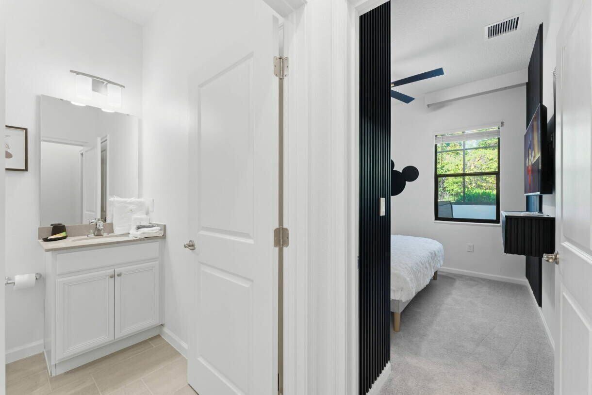 A modern bathroom with a white vanity, a mirror, and a towel rack.