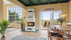 Una habitación acogedora con chimenea, muebles de madera y ventanas amplias que dan al exterior.