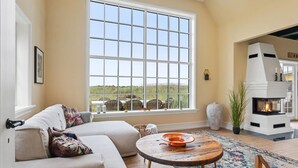 Un salón amplio con un ventanal grande, una chimenea y una zona de estar acogedora.