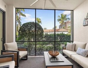 Ein Zimmer mit großem Fenster, zwei Sofas, einem Couchtisch und einem Deckenventilator.