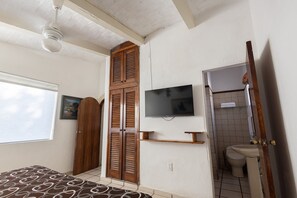 A bedroom with a bed, a wardrobe, a television, and a bathroom with a toilet and sink. - Mar y Cocos Hotel & Villas  (Manzanillo)