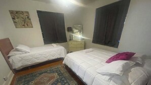 Ein Schlafzimmer mit zwei Betten, einem Nachttisch, einer Lampe und einem gemusterten Teppich.