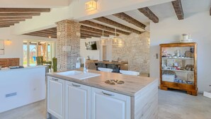 Een moderne keuken met een centraal eiland, een stenen muur en zichtbare houten balken.