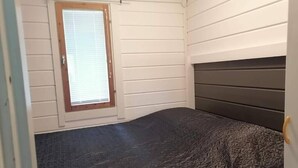 Ein Zimmer mit einem Bett, einem Fenster mit Jalousien und einer Tür.
