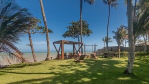 Een strandgebied met een houten pergola, lounge stoelen en picknicktafels.