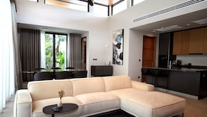 Una sala de estar moderna con un sofá seccional color beige, una mesita redonda negra y una alfombra negra.