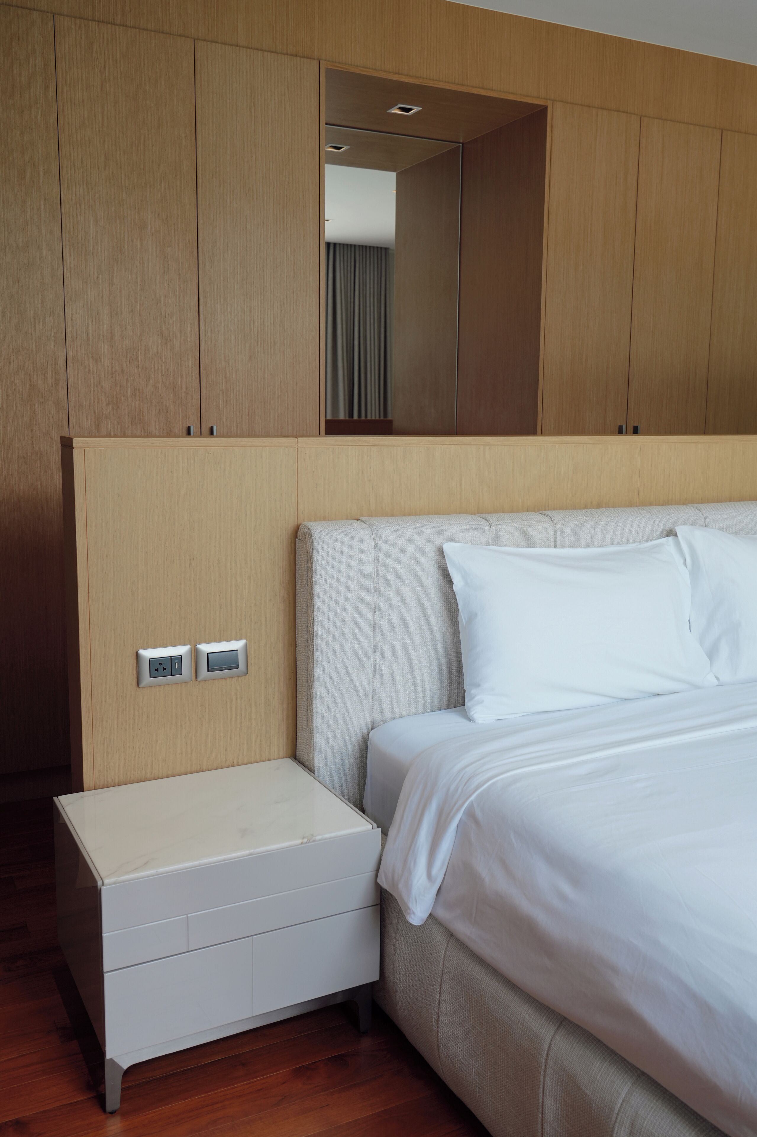 Una habitación de hotel moderna con una cama grande, una mesita de noche y un armario.