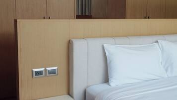 Una habitación de hotel moderna con una cama grande, una mesita de noche y un armario.