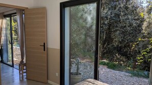 Une chambre avec une grande porte-fenêtre coulissante donnant sur un jardin.