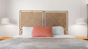 A bed with a woven headboard, white pillows, and a grey bedspread.
