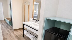 Ein modernes Badezimmer mit einem schwarzen Kühlschrank, einem Waschbecken und einem Spiegel.