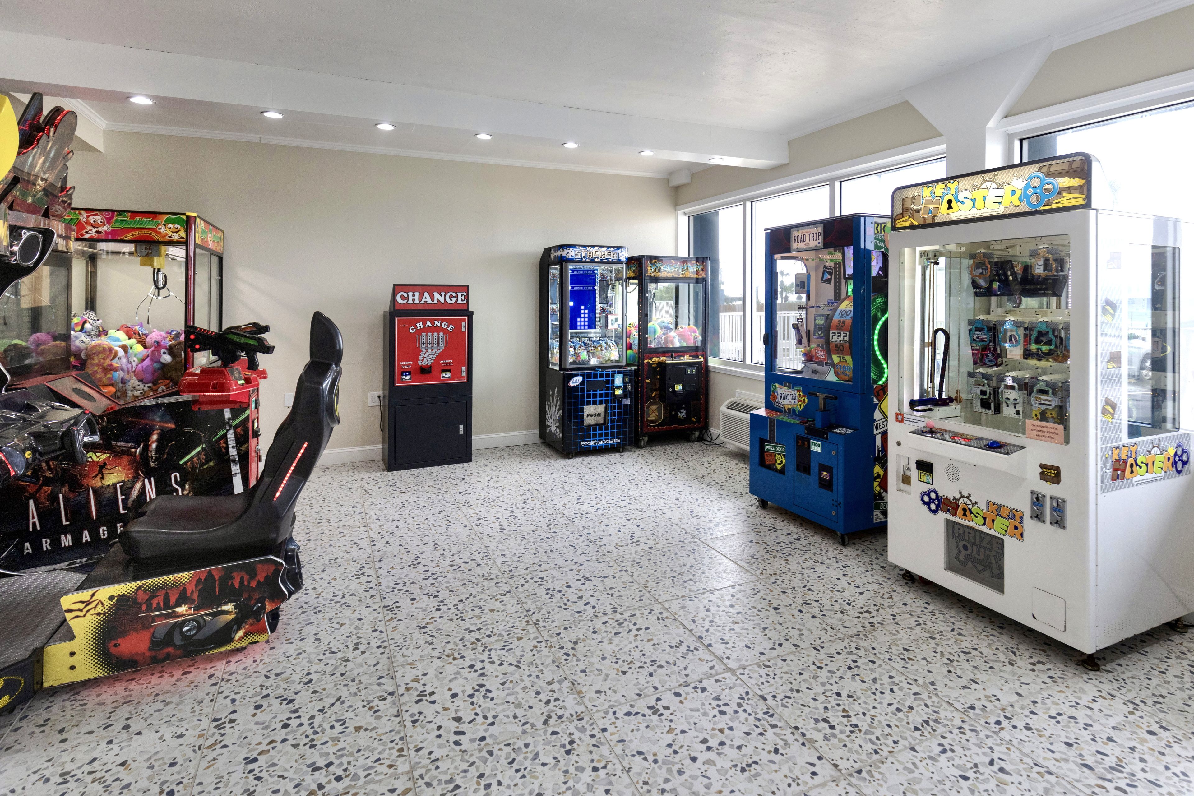 A room with arcade games, a claw machine, and a vending machine.