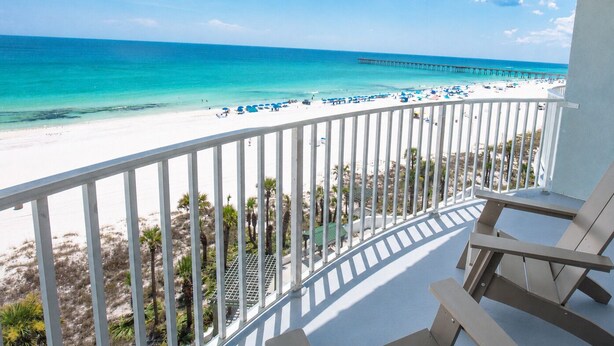 Ein Balkon mit Blick auf einen Strand, einen Steg und einen klaren Himmel.