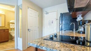 A kitchen with granite countertops, stainless steel appliances, and a backsplash. - One Bedroom King suite ADA (Parachute)