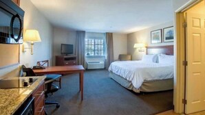 A hotel room with a bed, desk, chair, television, and a window. - One Bedroom King suite ADA (Parachute)