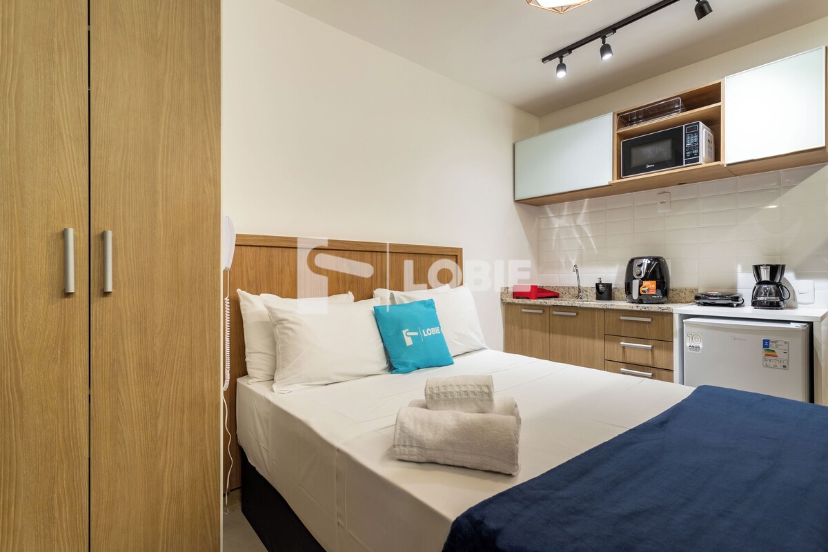 Une chambre d’hôtel comprenant un lit, une petite kitchenette, un four à micro-ondes, une machine à café et une armoire en bois.