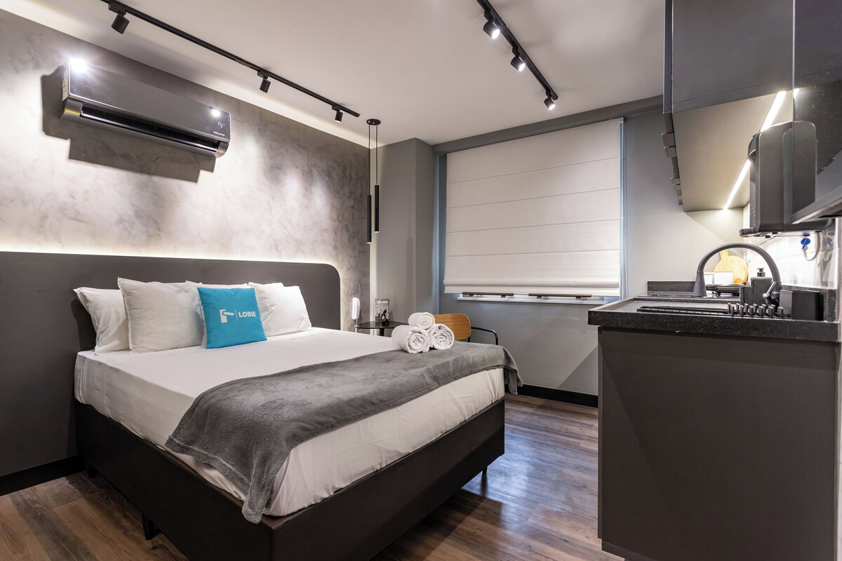 Une chambre d’hôtel moderne avec un grand lit, un bureau intégré et une fenêtre équipée de stores.