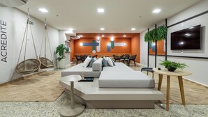 Une pièce moderne avec un canapé, des fauteuils suspendus, un téléviseur et une plante en pot.
