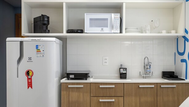 Une cuisine moderne avec un réfrigérateur blanc, un four à micro-ondes et des armoires en bois.