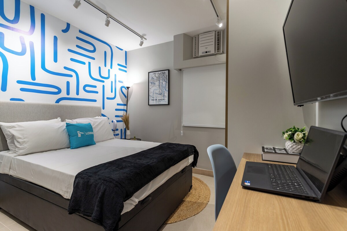 Une chambre à coucher moderne avec un lit, un bureau avec un ordinateur portable, une chaise et un mur orné de motifs abstraits.