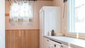 A compact laundry room with a washing machine, a drying rack, and a bench. - Pyry Cottage (Muurame)
