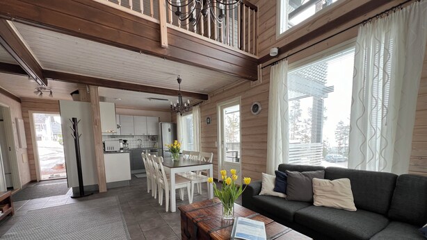 A spacious living area with a sofa, a wooden coffee table with a book, and a dining table with chairs. - Pyry Cottage (Muurame)