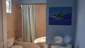 Un baño con ducha, inodoro, lavamanos y espejo.